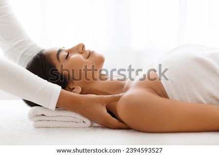 Side view of peaceful young indian lady having healing body massage from therapist at modern newest spa. Joyful woman getting relaxing body shoulders massage at wellness center