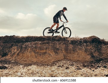 Side View Of A Person Riding A Trial Bicycle On The Hill. Horizontal Outdoors Shot.