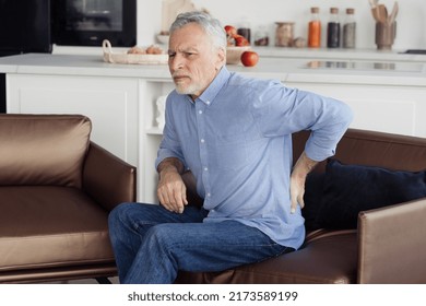 Side view photo of suffering senior man feeling lower back pain, sitting on comfortable orthopedic armchair in incorrect pose. Chronic injury, muscle inflammation and backache concept - Powered by Shutterstock