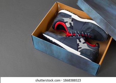 Side view of plain shoe box mockup on grey background. New pair of insulated sneakers inside shoe box. Space for text. 