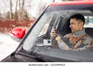 Side View Portrait Of Adult Man Enjoying Roadtrip In Winter And Taking Photos From Car, Copy Space