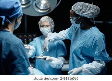 Side view portrait of African American female surgeon working with medical team in surgery and using tools copy space - Powered by Shutterstock