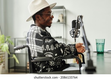 Side view portrait of African-American person with disability giving interview while recording podcast in studio