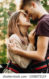 Side View Portrait Of An Amazing Couple Embracing And Laughing On A Zipline Platform Equipped Before Zip Lining.