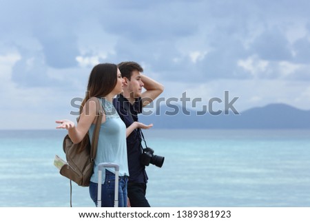 Side view portrait of an angry couple complaining on a cloudy vacation