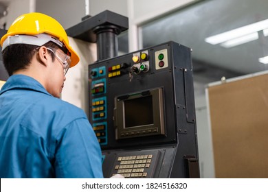 Side view portrait of Asian male engineer or mechanic worker controlling industry metal machine at industrial factory. man working at construction site in safety helmet and blue collar. copy space