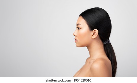 Side View Portrait Of Asian Woman Looking Aside At Copy Space Posing Shirtless Over Gray Studio Background. Profile Headshot Of Serious Attractive Korean Female. Panorama