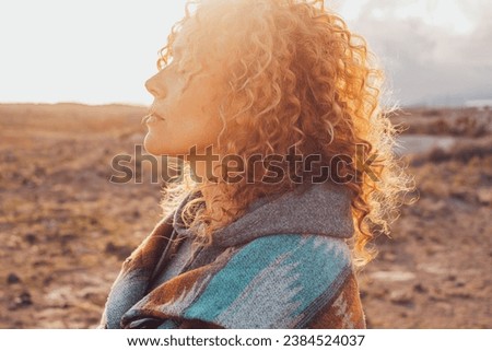 Side view portrait of attractive woman closing eyes and enjoying nature in outdoor leisure activity alone. People and contemplation meditation. Serene lifestyle female person. Long curly healthy hair