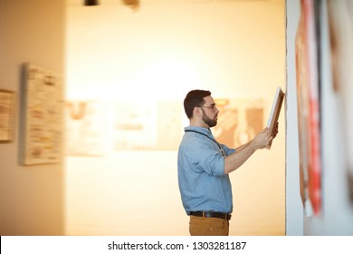 Side view portrait of bearded man holding picture in art gallery or museum, copy space