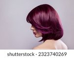 Side view portrait of beautiful fashion model woman with short purple colored hairstyle, looking away, showing her bright stylish colour of hair. Indoor studio shot isolated on gray background.