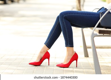 Side view portrait of a beauty woman legs with jeans and high heels sitting in a bench