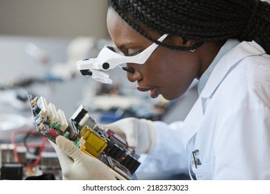 Side View Portrait Of Black Female Scientist Wearing Magnifying Glasses And Inspecting Electronic Parts In Quality Control Lab