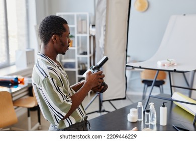 Side View Portrait Of Black Male Photographer Setting Up Camera In Photo Studio, Copy Space