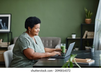 Side view portrait of black senior woman using laptop at home and smiling, copy space - Powered by Shutterstock