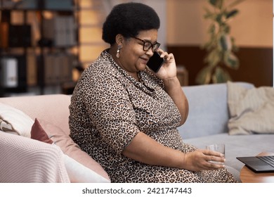 Side view portrait of Black senior woman speaking on phone at home and talking to friends and family copy space - Powered by Shutterstock