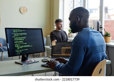 Side View Portrait Of Black Software Engineer Writing Code At Workplace In Office With Multiple Devices