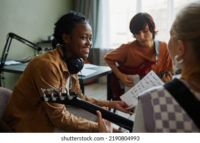 Side view portrait of black young woman writing music with band and smiling happily - Powered by Shutterstock