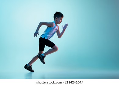 Side view portrait of boy in motion, running athelete training isolated over white background in neon. Concept of action, sport, healthy life, competition, motion, physical activity. Copy space for ad