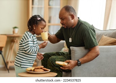Side view portrait of caring black father sharing tea and cookies with cute daughter - Powered by Shutterstock