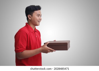 Side view portrait of cheerful Asian delivery courier man bringing and showing the box package. Online shopping concept. Isolated image on white background
