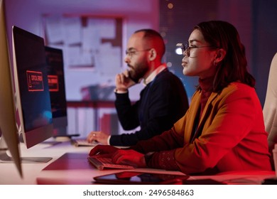 Side view portrait of computer programmers working in cybersecurity department with red emergency lights copy space - Powered by Shutterstock