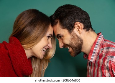 Side View Portrait Of Couple Standing, Bumping Heads Together And Looking At Each Other Isolated Over Green Background. Concept Of Love, Relationship, Facial Expression, Emotions, Feelings And Ad