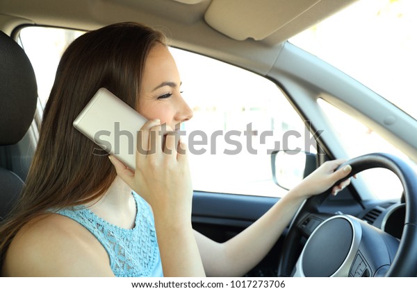 Side view portrait of a distracted driver calling on\
phone driving a car