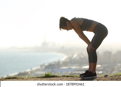 Side view portrait of an exhausted runner resting after sport in city outskirts