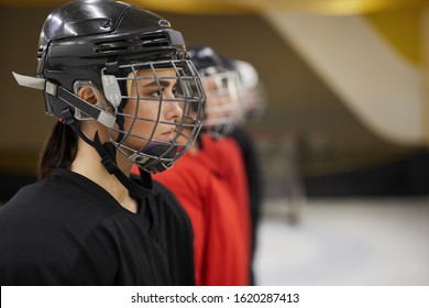 Side View Portrait Of Female Hockey Team Standing In Line Before Match On Rink, Focus On Beautiful Woman Wearing Sports Helmet In Foreground, Copy Space