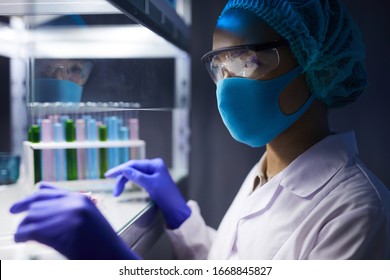 Side View Portrait Of Female Scientist Wearing Face Mask And Protective Gear Working On Research In Laboratory, Copy Space