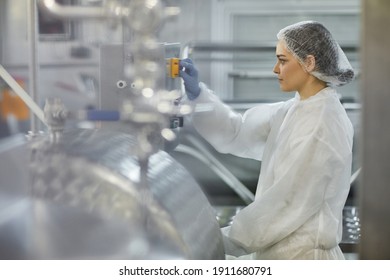 Side View Portrait Of Female Worker Pushing Button While Operating Machine Units At Clean Food Production Factory, Copy Space