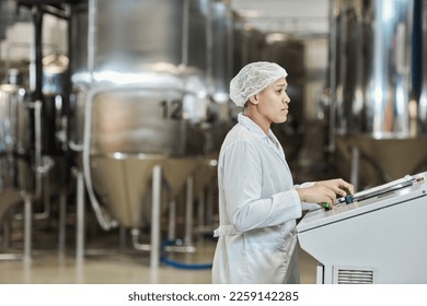 Side view portrait of female worker wearing lab coat operating equipment at food factory, copy space - Powered by Shutterstock