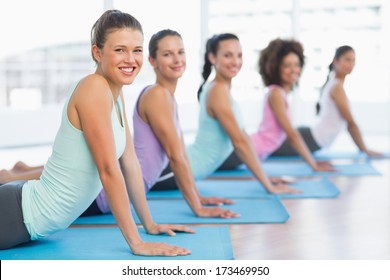 Side view portrait of a fit class doing the cobra pose in a bright fitness studio - Powered by Shutterstock