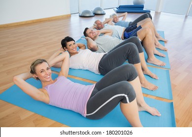 Side view portrait of fitness class lying on mats in row at yoga class