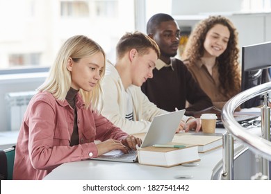 Side view portrait of group of students using laptops while studying in college, blonde girl typing in foreground, copy space - Powered by Shutterstock