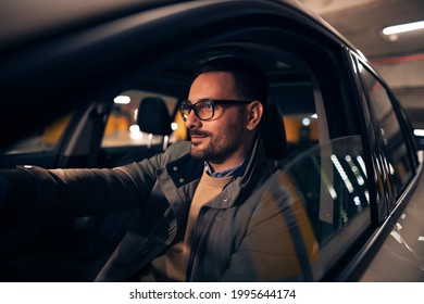 Side view portrait of a handsome stylish man driving car at night - Shutterstock ID 1995644174