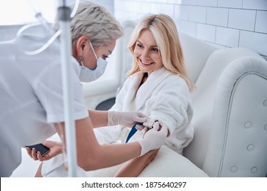 Side view portrait of happy cheerful talking with professional doctor while receiving IV infusion in beauty clinic - Powered by Shutterstock