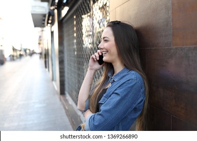 Side view portrait of a happy girl profile talking on phone in the street
