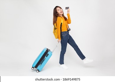 Side View Portrait Of Happy Young Asian Woman Walking With Travel Bag And Holding Credit Card Isolated On White Background