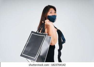 Side View - Portrait Of Healthy Asian Chubby Woman Wearing Mask And Holding Shopping Bags On White Background.