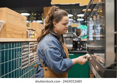 Side view portrait of independent adult woman with Down syndrome working with oven in cafe or bakery - Powered by Shutterstock