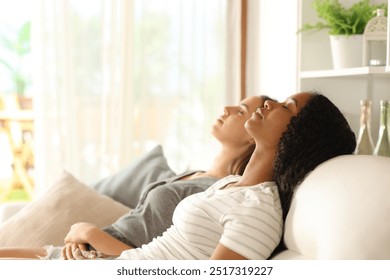 Side view portrait of an interracial couple relaxing or sleeping sitting on a couch at home - Powered by Shutterstock