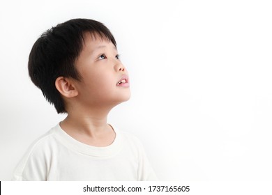 Side View Portrait Of A Little Asian Boy Looking Up Against White Background.