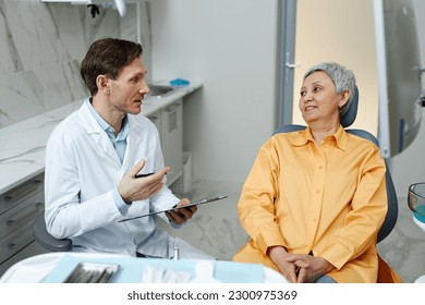 Side view portrait of male dentist consulting senior woman in dental clinic - Powered by Shutterstock