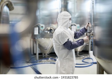 Seitenbild des männlichen Arbeitnehmers mit Schutzanzug beim Betrieb von Geräten in modernen Chemieanlagen, Kopienraum