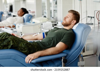 Side View Portrait Of Military Man Donating Blood While Laying In Chair At Plasma Donation Center