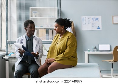 Side view portrait of overweight black woman talking to doctor in medical clinic, copy space - Powered by Shutterstock