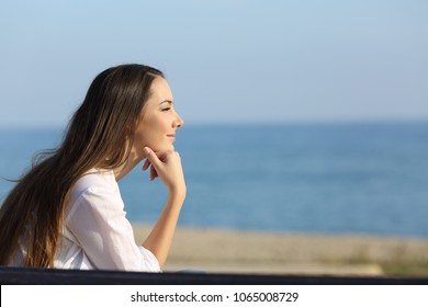 Side view portrait of a pensive woman looking forward on the beach