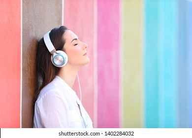 Side view portrait of a relaxed girl listening to music in a colorful street - Powered by Shutterstock