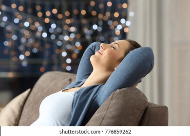 Side View Portrait Of A Relaxed Happy Woman Resting Sitting On A Couch In The Night At Home